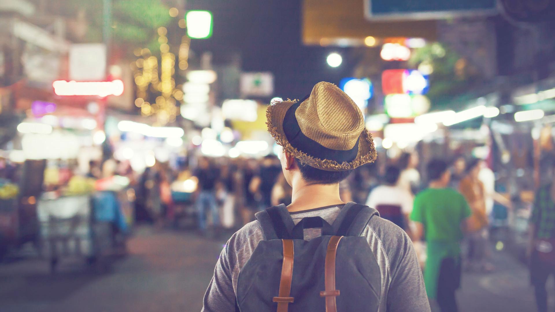 Young Asian traveling backpacker in Khaosan Road night market in evening in Bangkok, Thailand