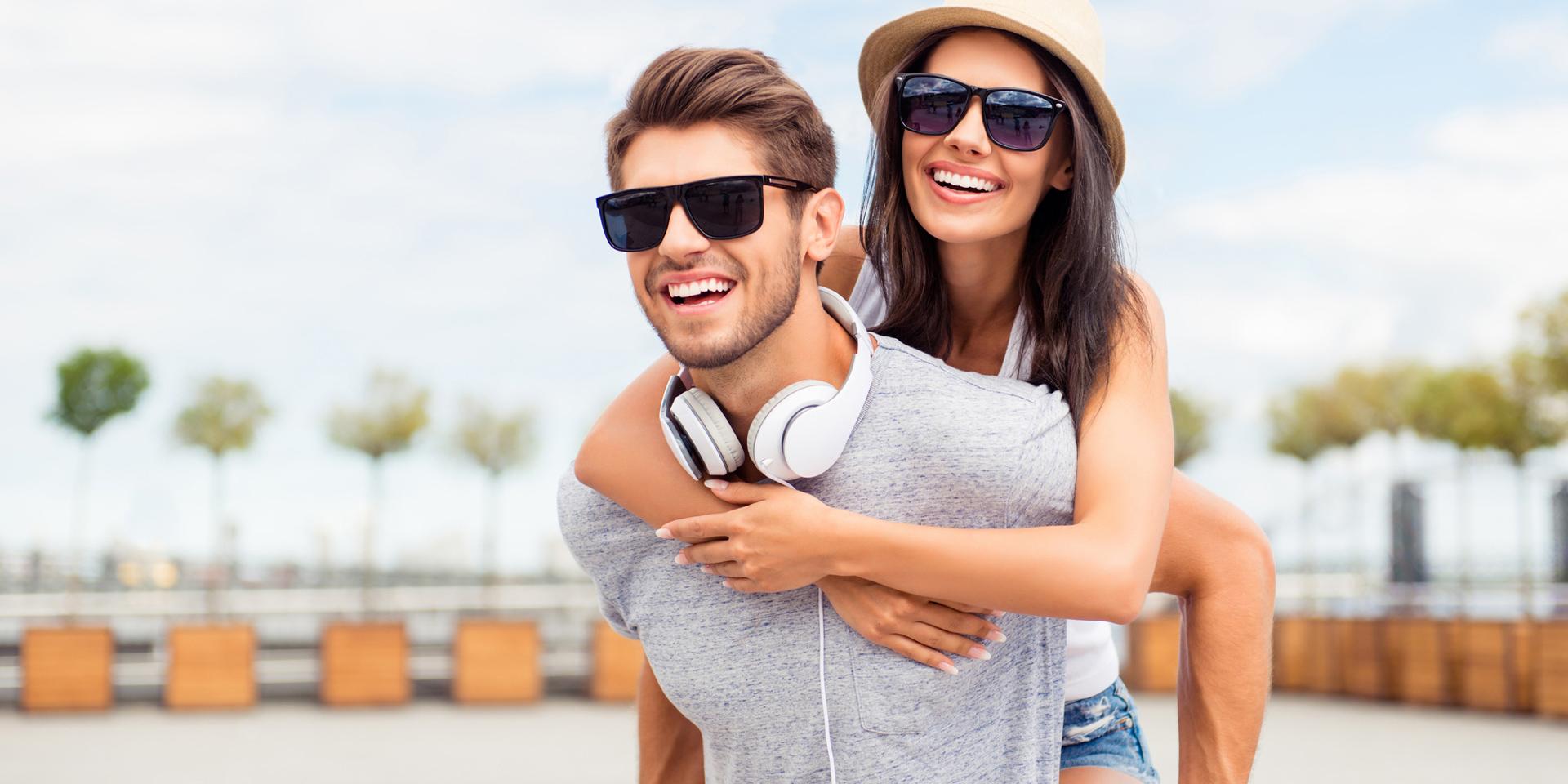 Handsome man carrying his smiling girlfriend on back