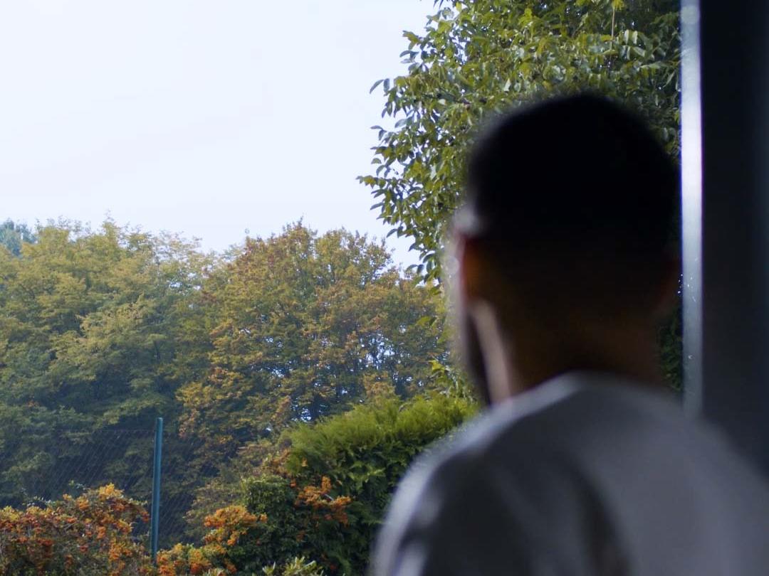 A young man wearing BlueGuard glasses, looking out the window.