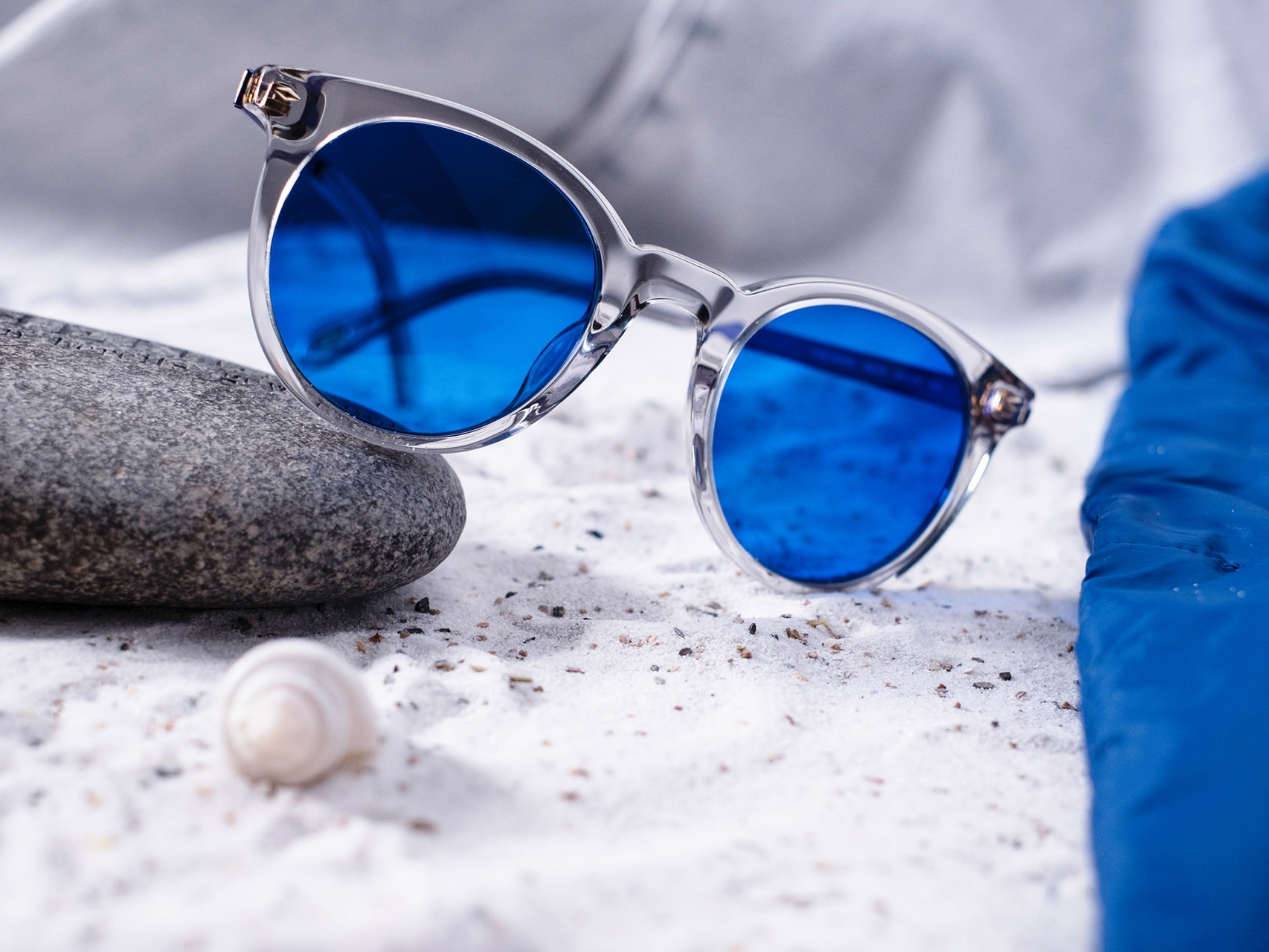 Picture of a pair of sunglasses with blue tint half laid on a stone