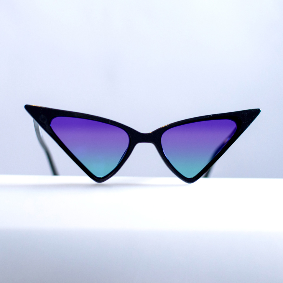Extraordinary cat eye sunglasses on a white surface with cyan-purple-gradient tint